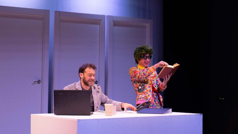 Escena de El diario de Lucas con Lucas en un escritorio y un personaje mágico con un libro.