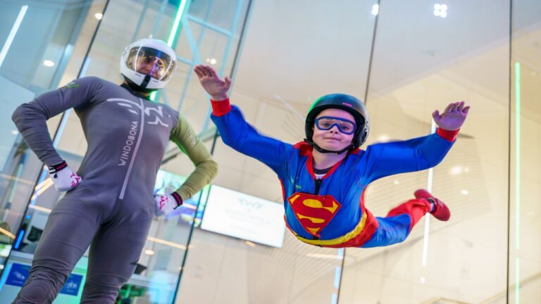 Instructor de Windobona Madrid acompaña a un niño mientras vuela en el túnel de viento.